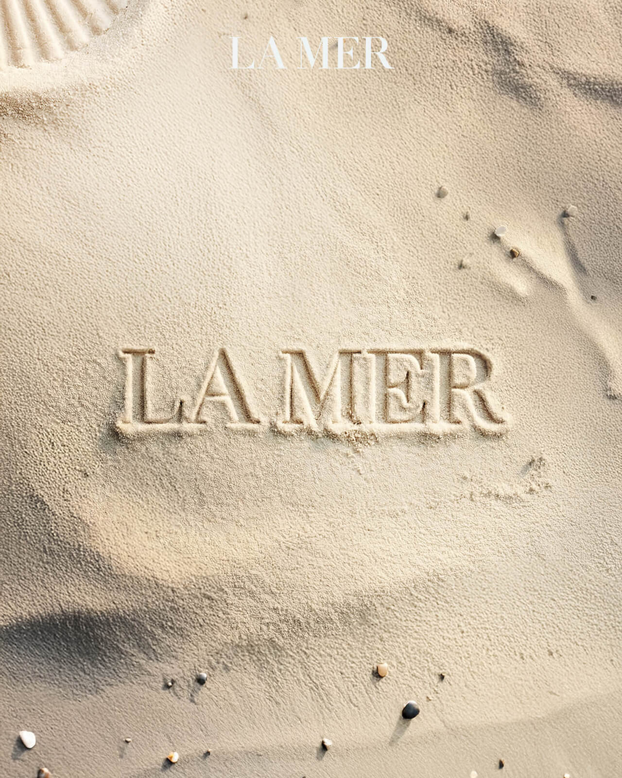 'La Mer' written in the sand on a beach.