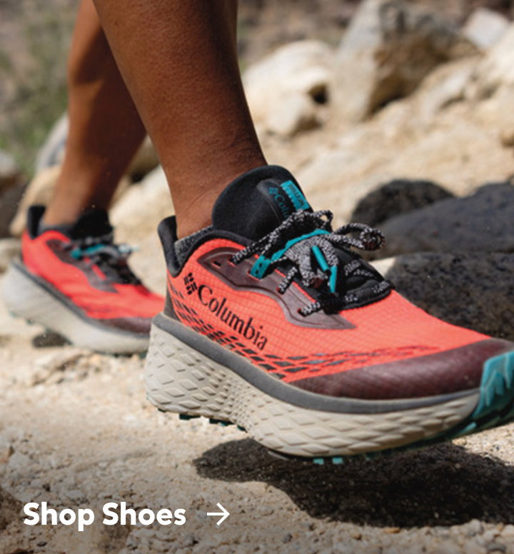 Close-up of red and teal hiking shoes on rocky ground with text: Shop Shoes