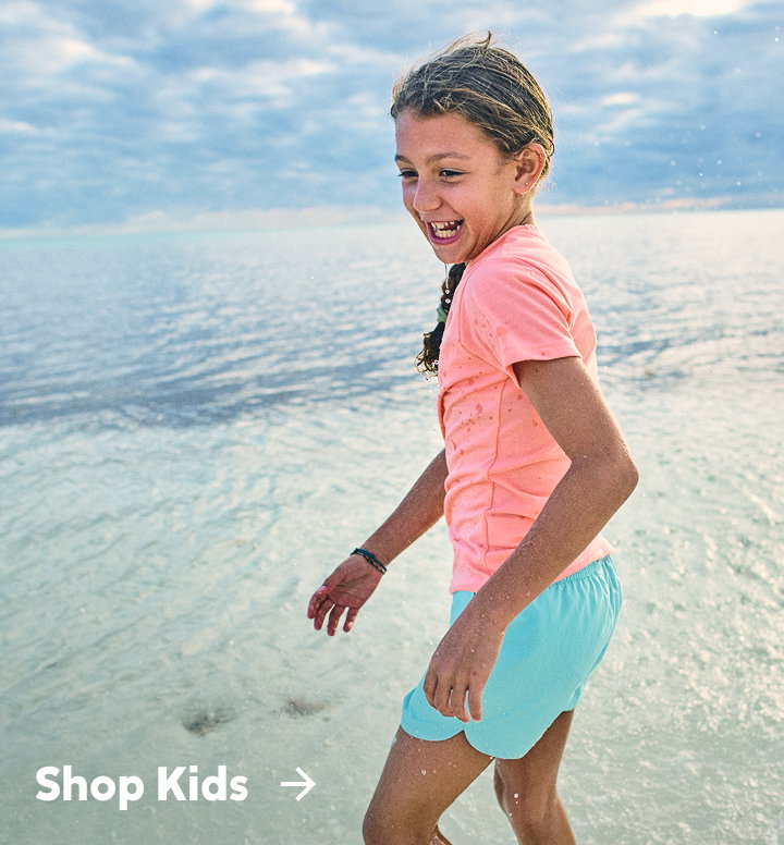 A little girl playing on the beach with text: Shop Kids