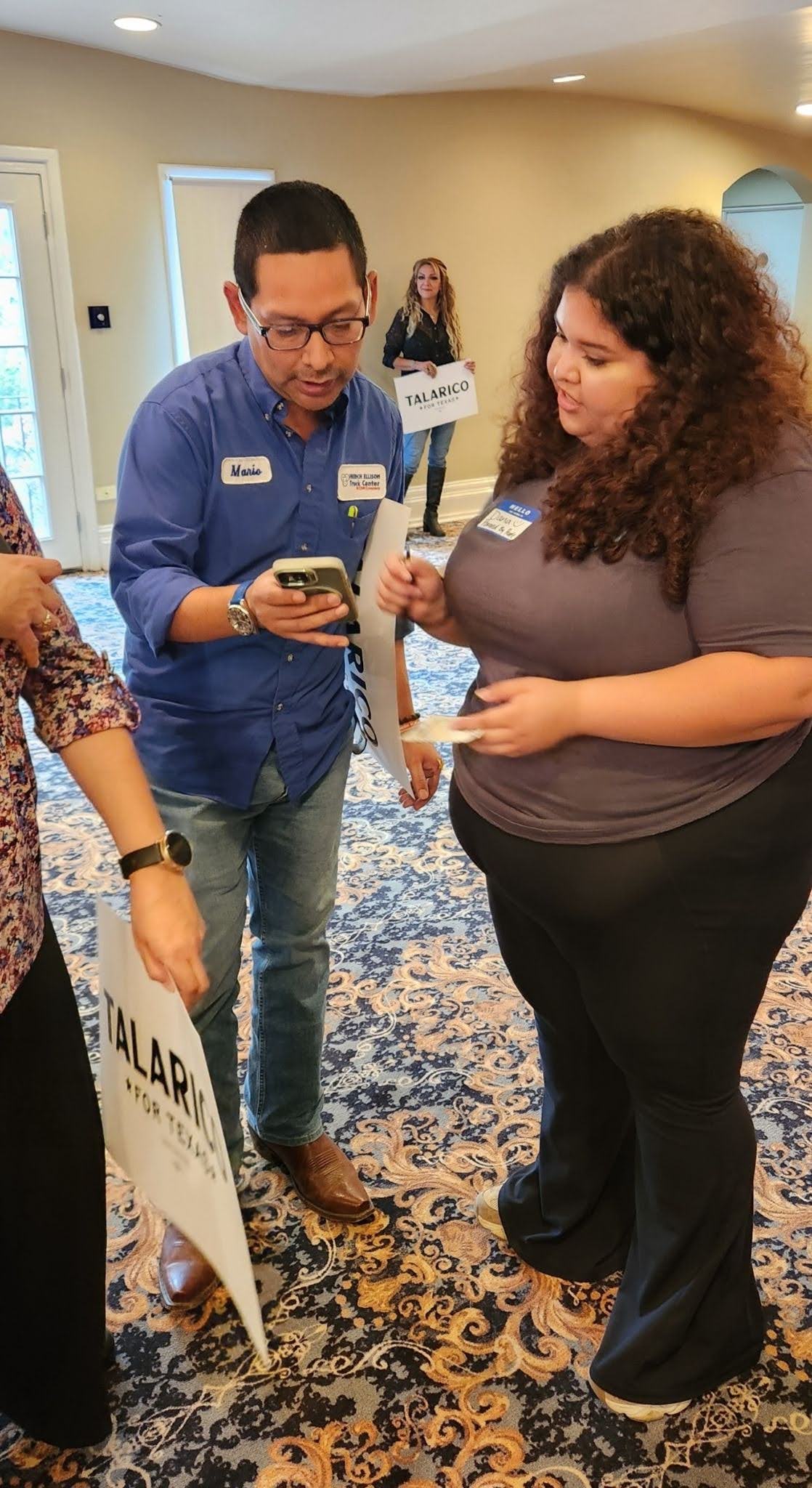 A man in a blue shirt (left) and a PxP volunteer (right), both looking at the man's phone