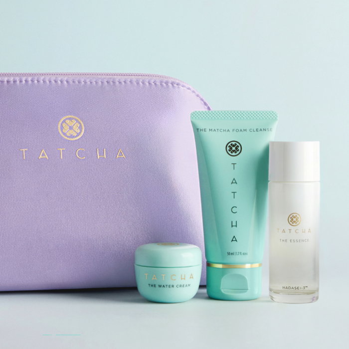 The Travel Set Curator from Tatcha: showcasing the purple travel bag, travel size Water Cream, travel size Matcha Foam Cleanse, and travel size Essence.