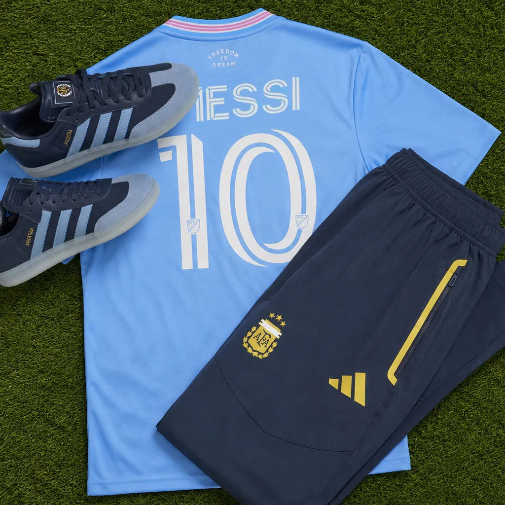 Messi #10 Argentina jersey in light blue with matching black Adidas sneakers and navy shorts on grass background.