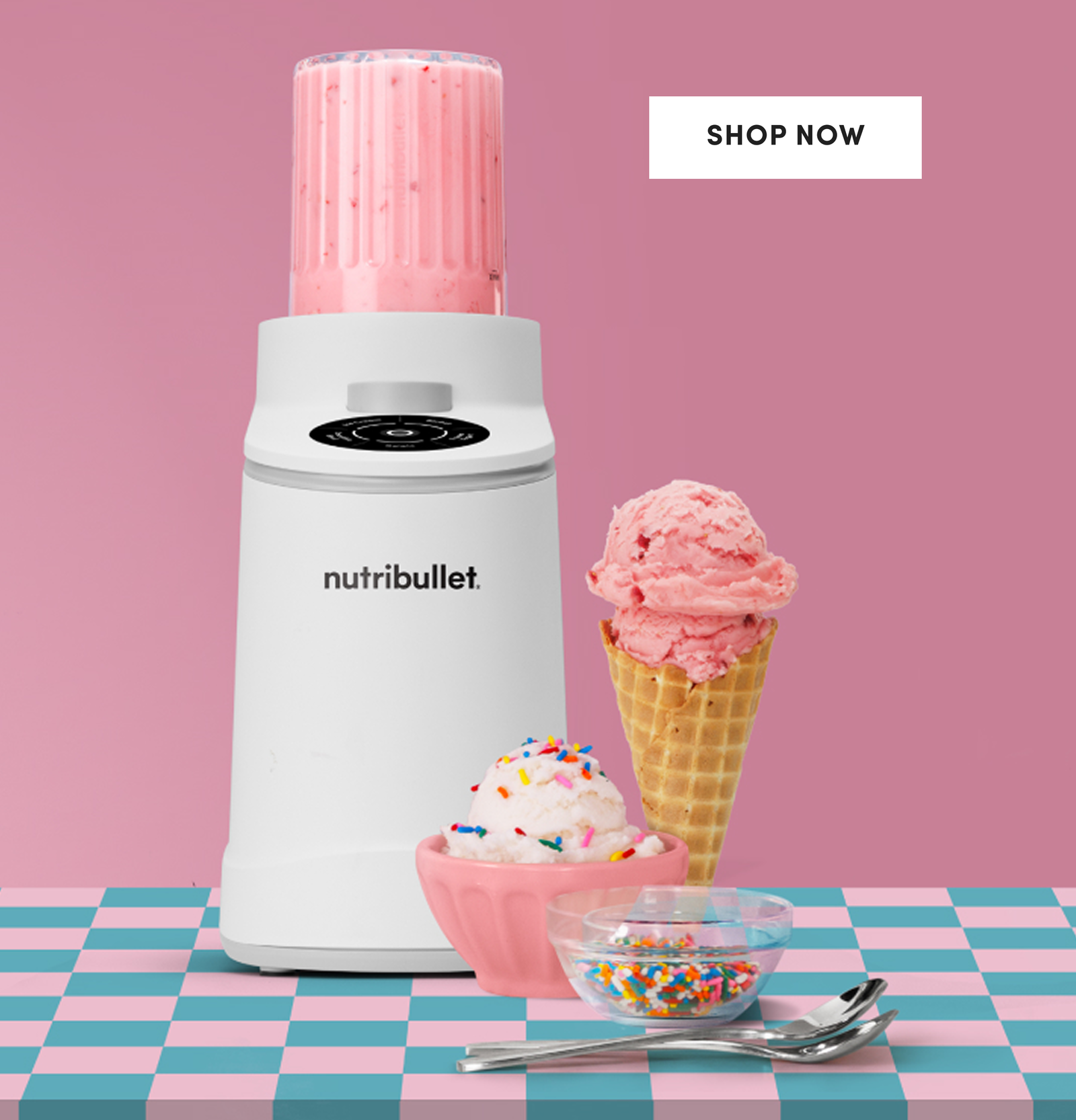 A white nutribullet Chill™ Ice Cream Maker beside a pink ceramic bowl and a waffle cone stacked with strawberry scoops.