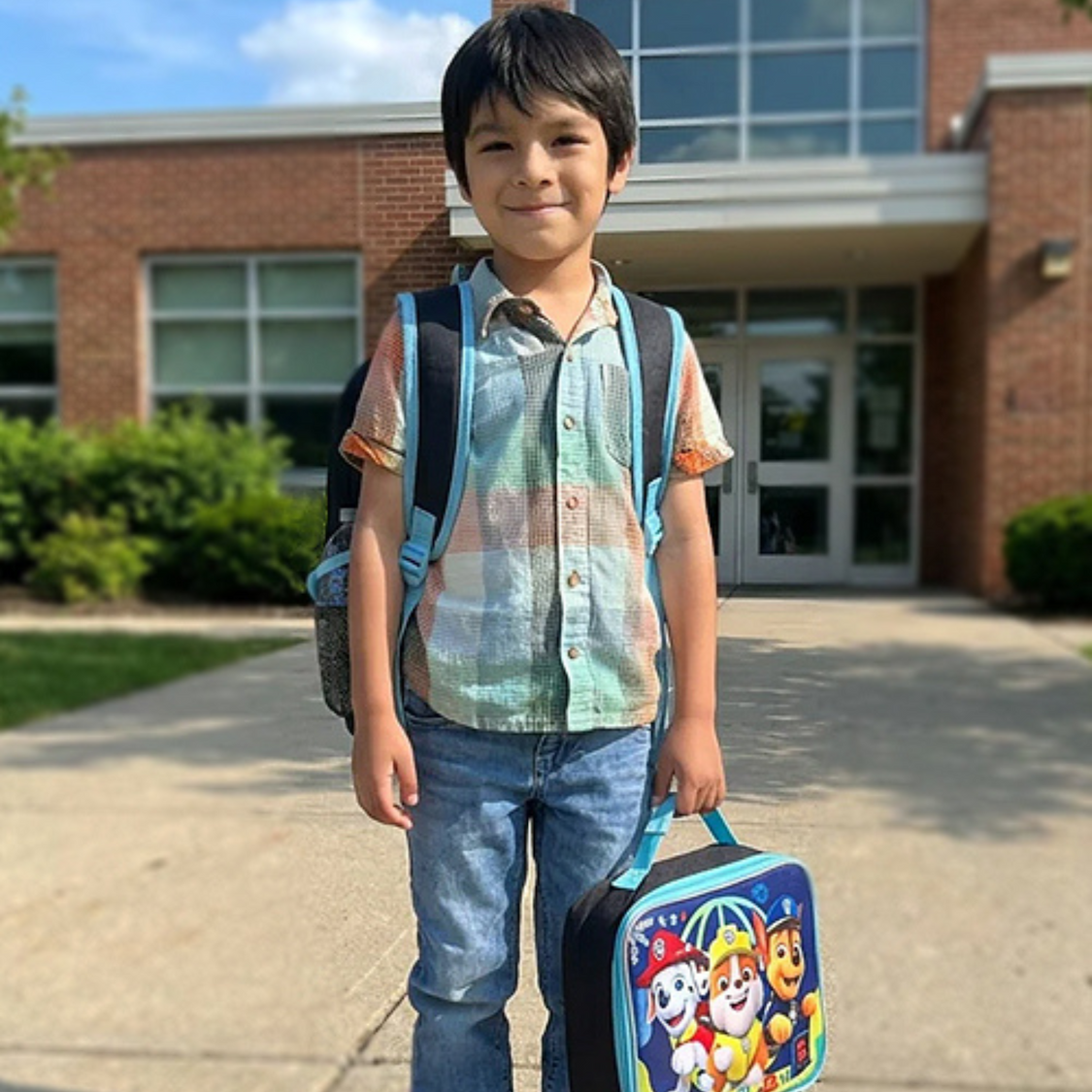 Boy carrying backpack and holding lunch box