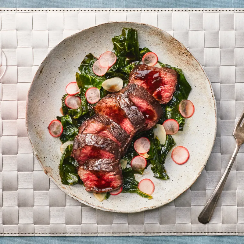 Chris Steak for one plated on a stone plate on a silver woven placemat.