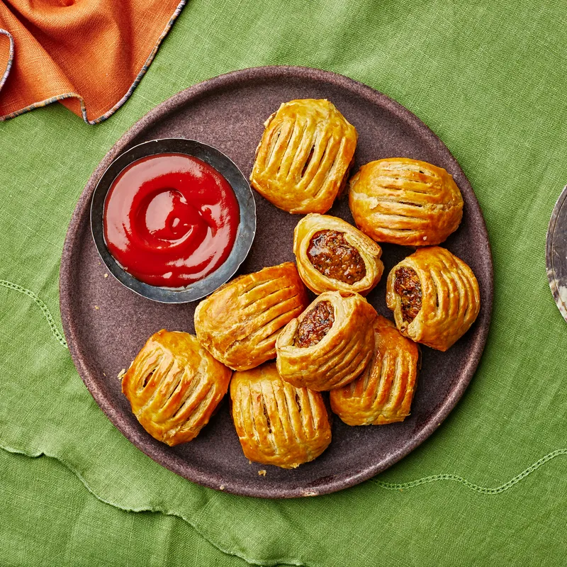 Plate of zucchini sausage rolls on green linen.