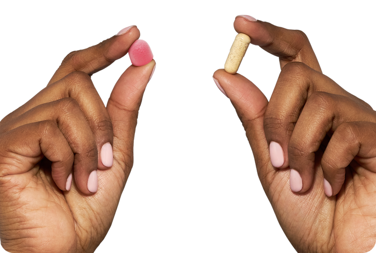 Hands holding a MegaFood gummy and a capsule