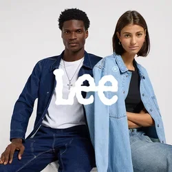 Man en vrouw zitten naast elkaar op een wit blok, beiden gekleed in denim outfits tegen een effen lichte achtergrond.