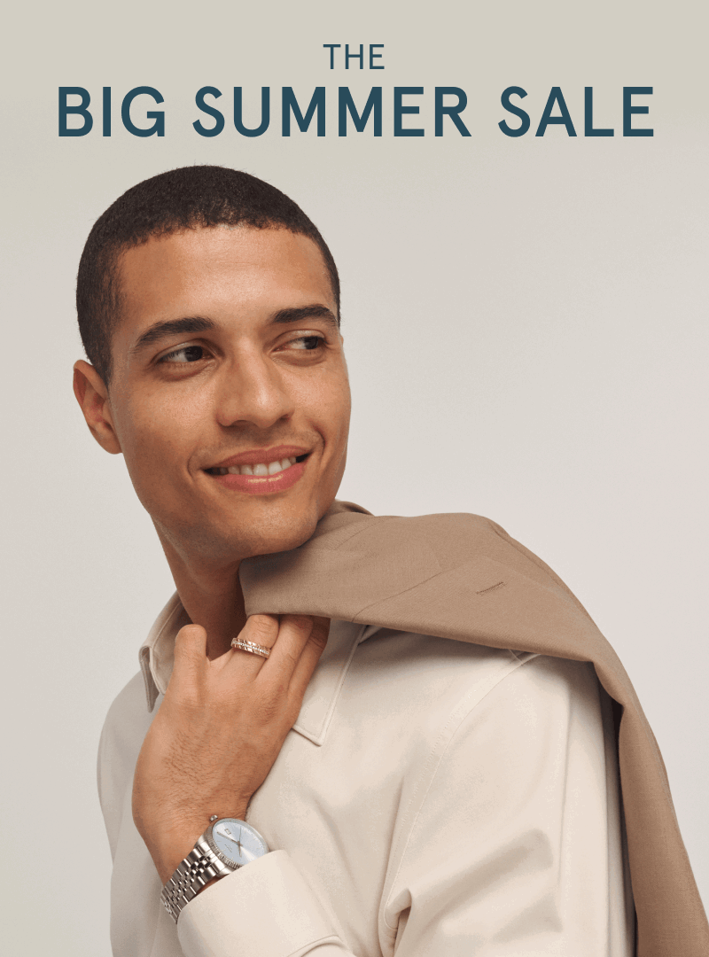 Man wearing a gold band ring and silver watch with a jacket draped over his shoulder.  The big summer sale.