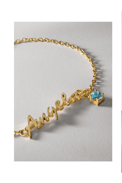 Yellow gold name necklace with an aquamarine blue gemstone charm reading Angela.