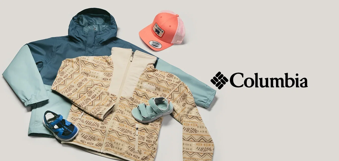 Dos chaquetas infantiles, una beige con estampado y otra azul, con sandalias a juego y una gorra de béisbol rosa sobre un fondo claro.