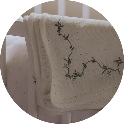 Bluebell Knit Blanket draped over crib