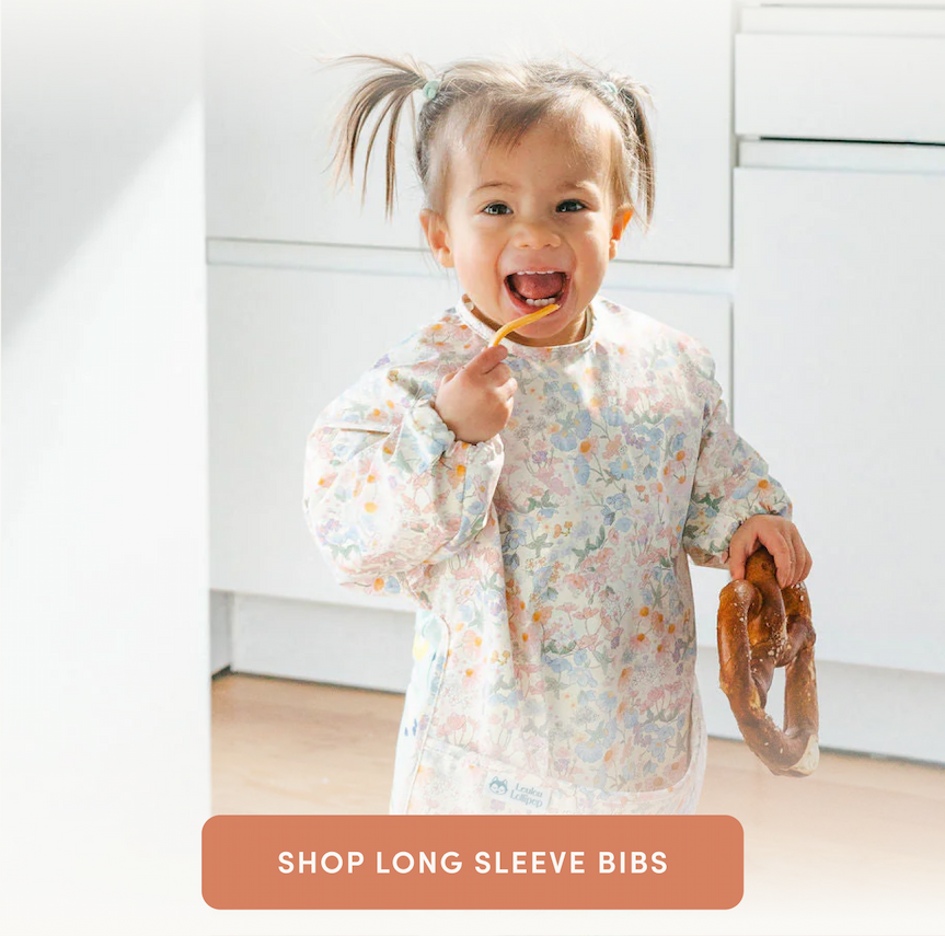 toddler girl with pigtails eating a large bread pretzel