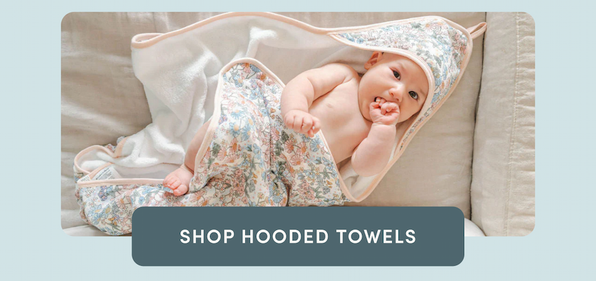 baby lying on a couch wearing a floral hooded towel