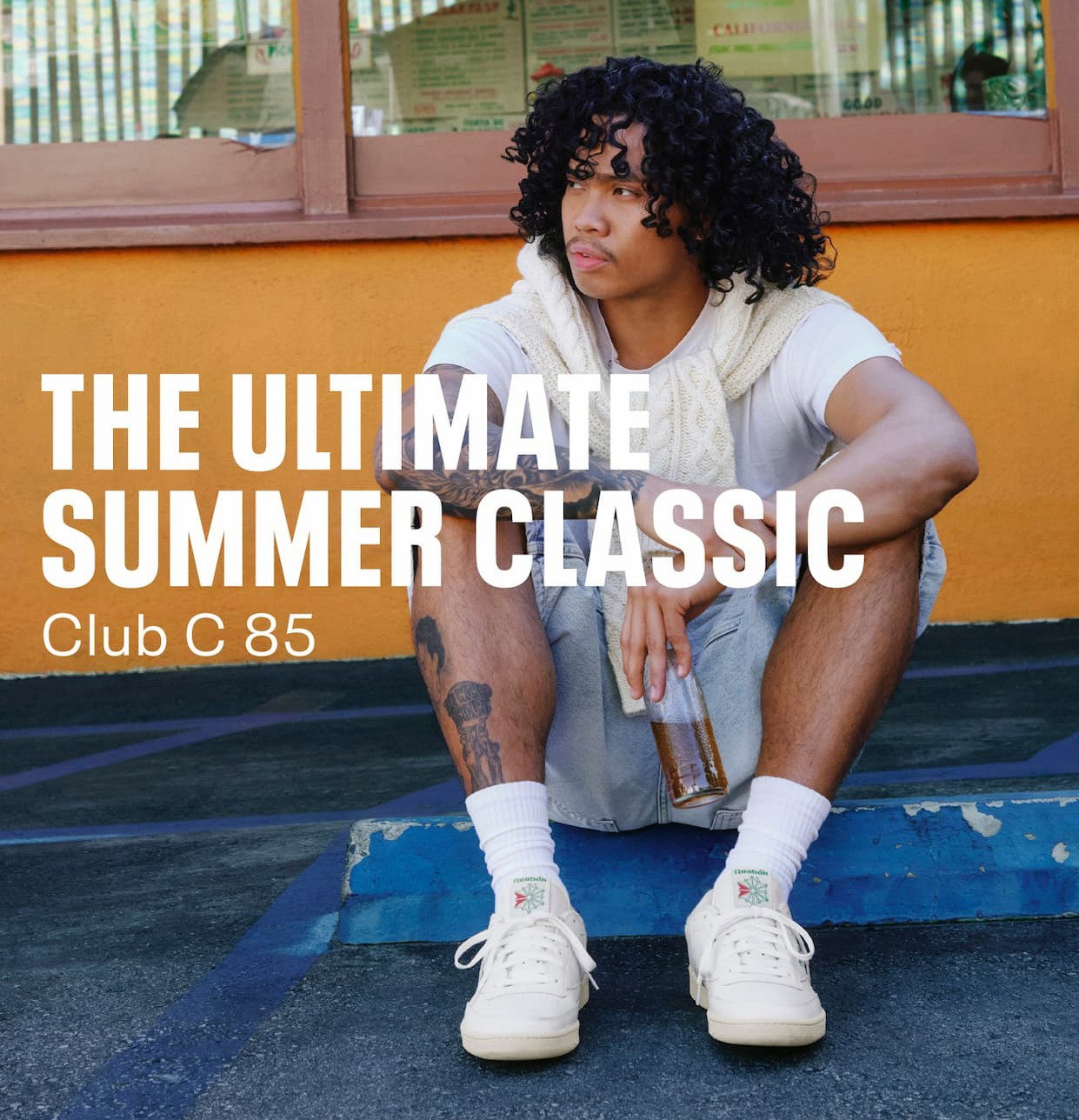 Person wearing Club C 85 Vintage sneakers sits outdoors. Text reads: “THE ULTIMATE SUMMER CLASSIC. Club C 85.”