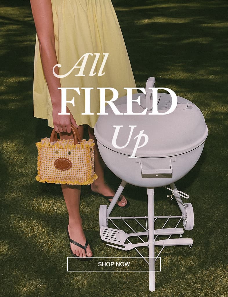 Model carrying the Hammitt Olympia Crossbody Sml in Pink Lemonade beside a backyard barbecue grill.