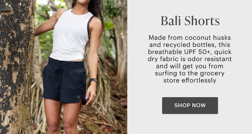 Bali Shorts - Woman in black Bali Shorts and white tanks in tropical trees. 