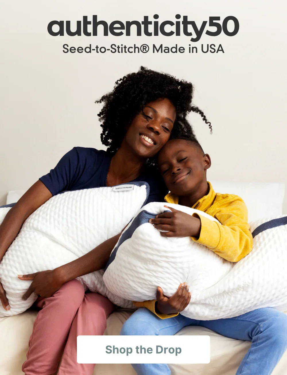 Mother and son sitting on the edge of the bed, snuggled together and hugging their Custom Comfort Pillows.