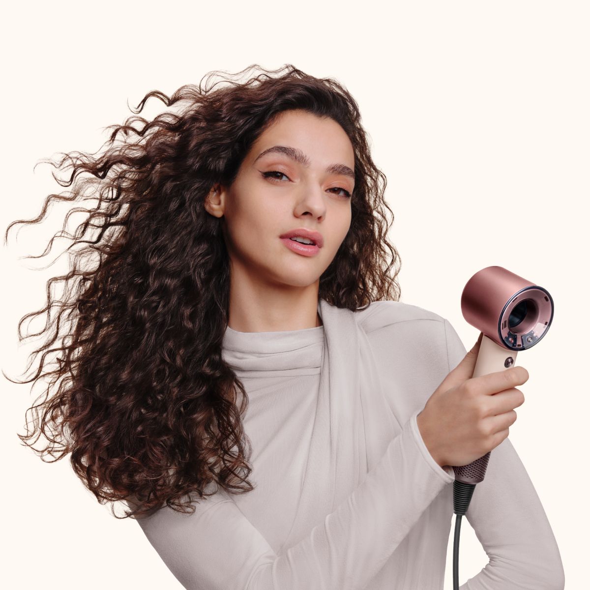 Model with curly hair uses the Dyson Supersonic Travel hair dryer to dry her hair.