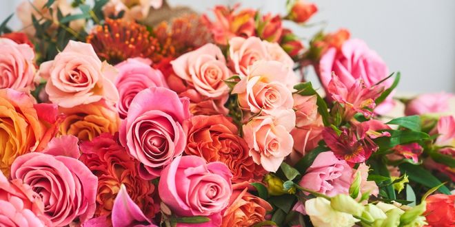 Image shows a summer bouquet in pinks and oranges laying on a table.