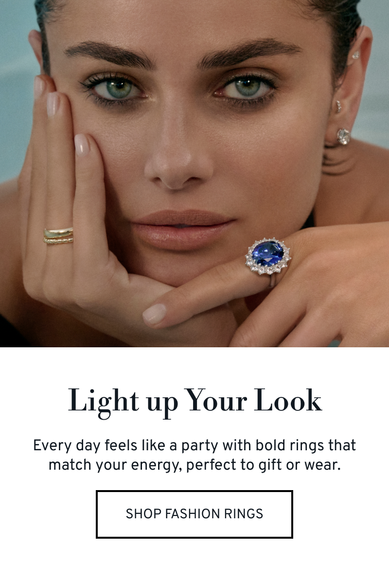 Model in a pool wearing a sapphire statement ring and separate ring stack. Light up your look. Click to Shop  Fashion Rings
