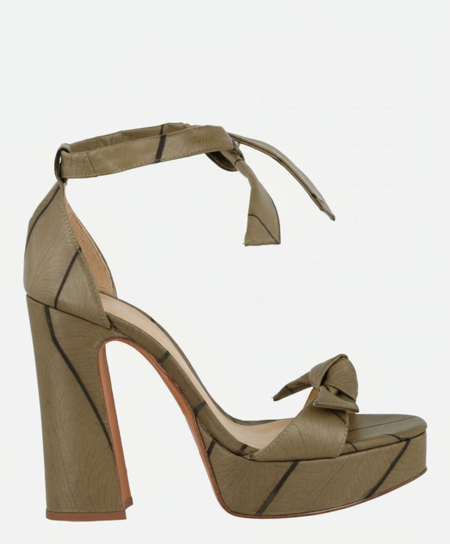 A green platform sandal with a bow detail and ankle strap, featuring a leaf-like pattern.