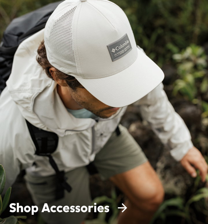 A man wearing a white ball cap, jacket, and shorts with text: Shop Accessories