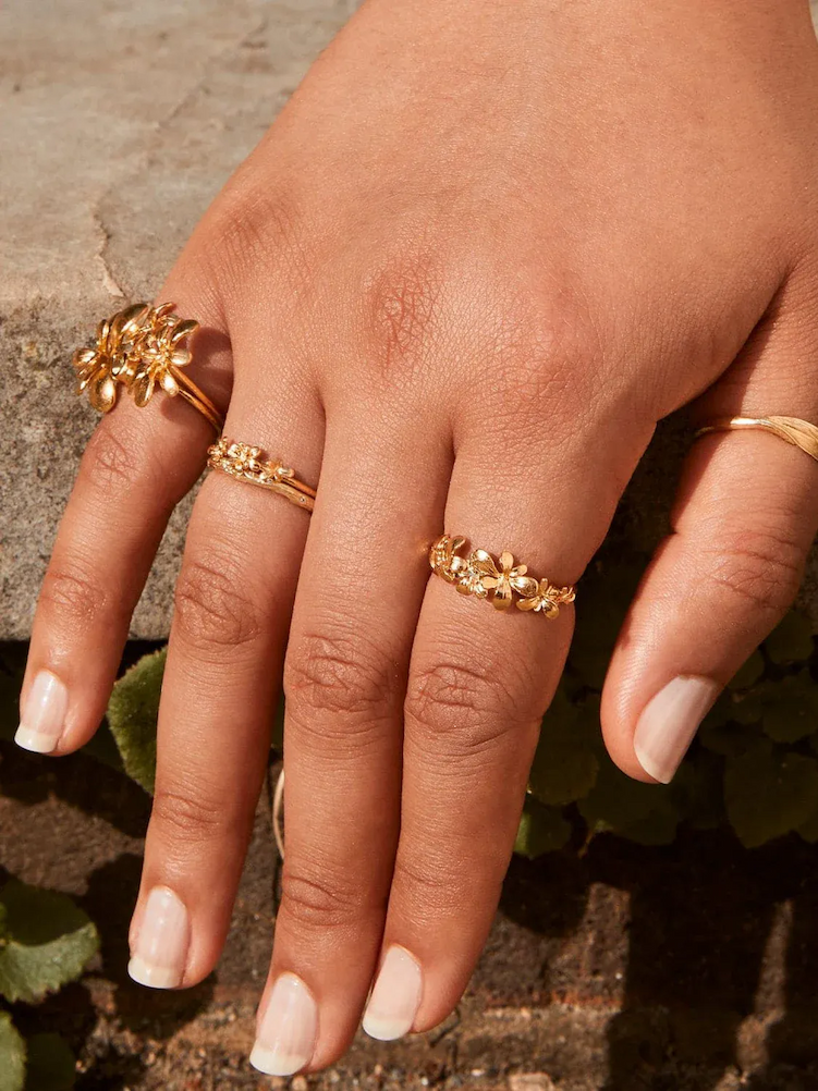 Hand wearing a collection of delicate gold stacking rings.
