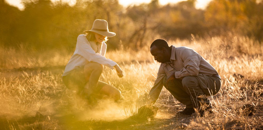 Safari guide sharing wildlife tracking skills with a guest during a guided walking safari
