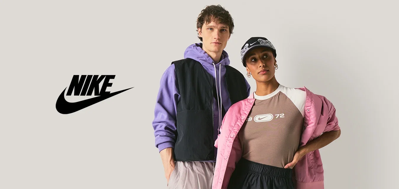 Due modelle che posano contro uno sfondo neutro; una indossa una felpa con cappuccio e un gilet viola, l'altra una giacca rosa e un berretto nero, entrambe in abbigliamento sportivo casual.