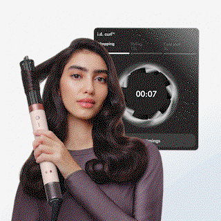 Model curls her hair with the Dyson Airwrap Co-anda2x multi-styler and dryer next to a screen of the MyDyson app