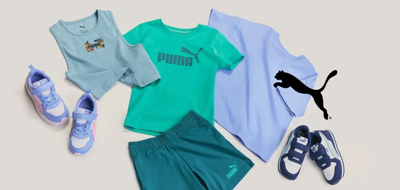Tres conjuntos de ropa casual infantil y pares de zapatillas deportivas dispuestos sobre un fondo claro, incluyendo camisetas, pantalones cortos y zapatillas.