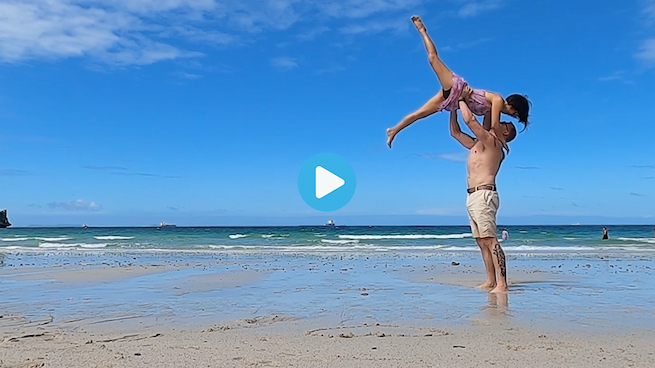 Man holding a woman in the air at the beach