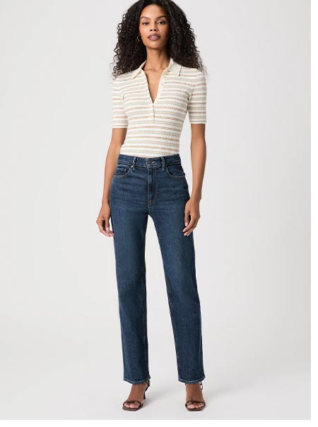 A woman wearing a white and yellow striped polo and dark denim jeans.