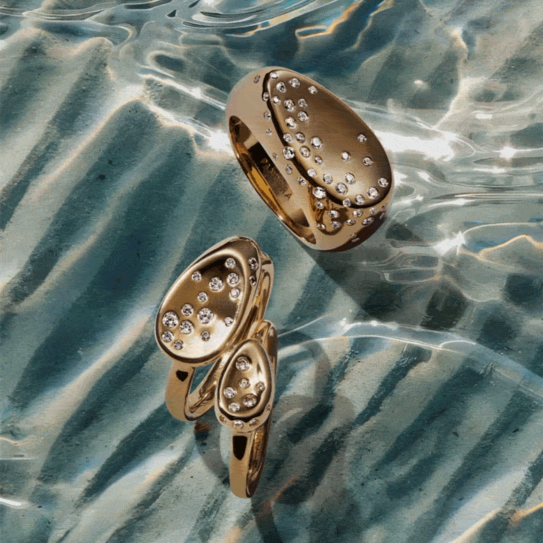 A pair of 14k gold-plated pavé earrings on shimmering water.