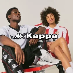 Dos personas con ropa deportiva Kappa están sentadas en un carrito de plataforma rojo sobre un fondo liso.