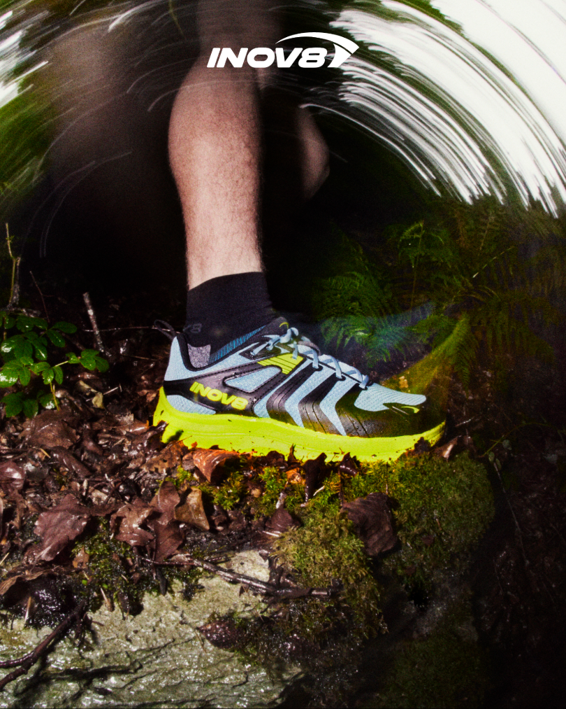 A profile view of a TRAILTALON MAX shoe flying through a muddy trail