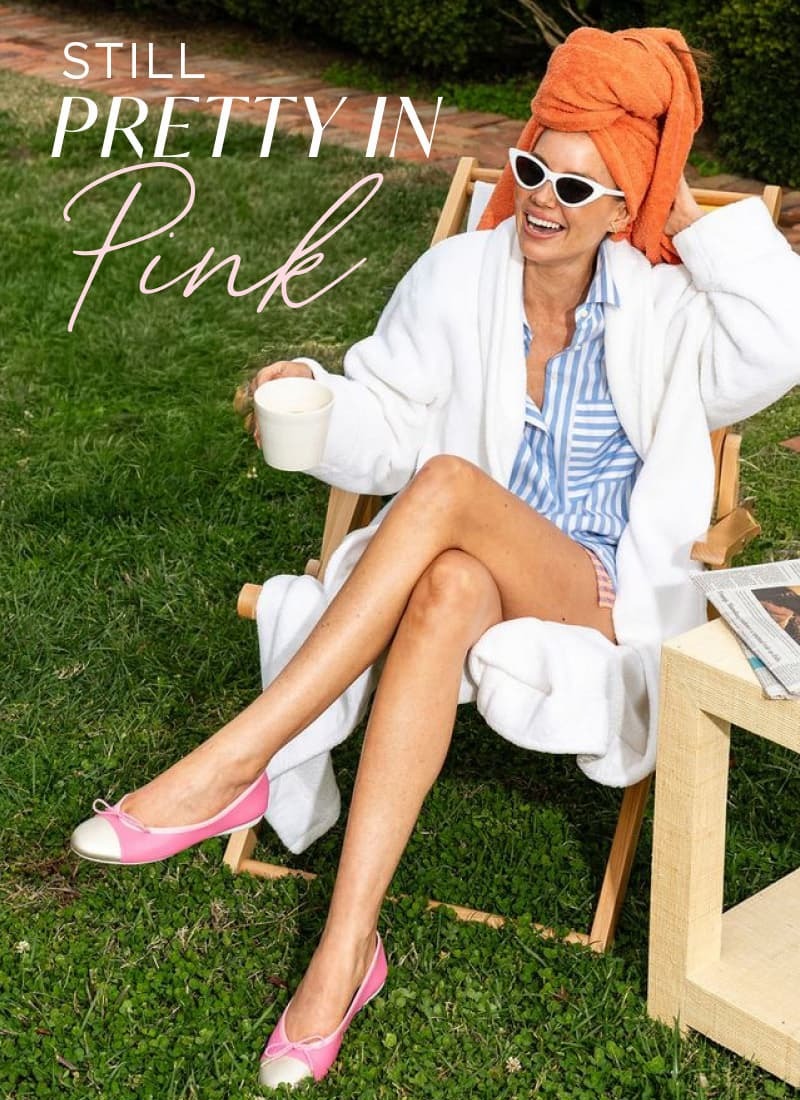 Still Pretty in Pink. Woman in white jacket, striped shirt and coral hat wearing pink shoes on grass.
