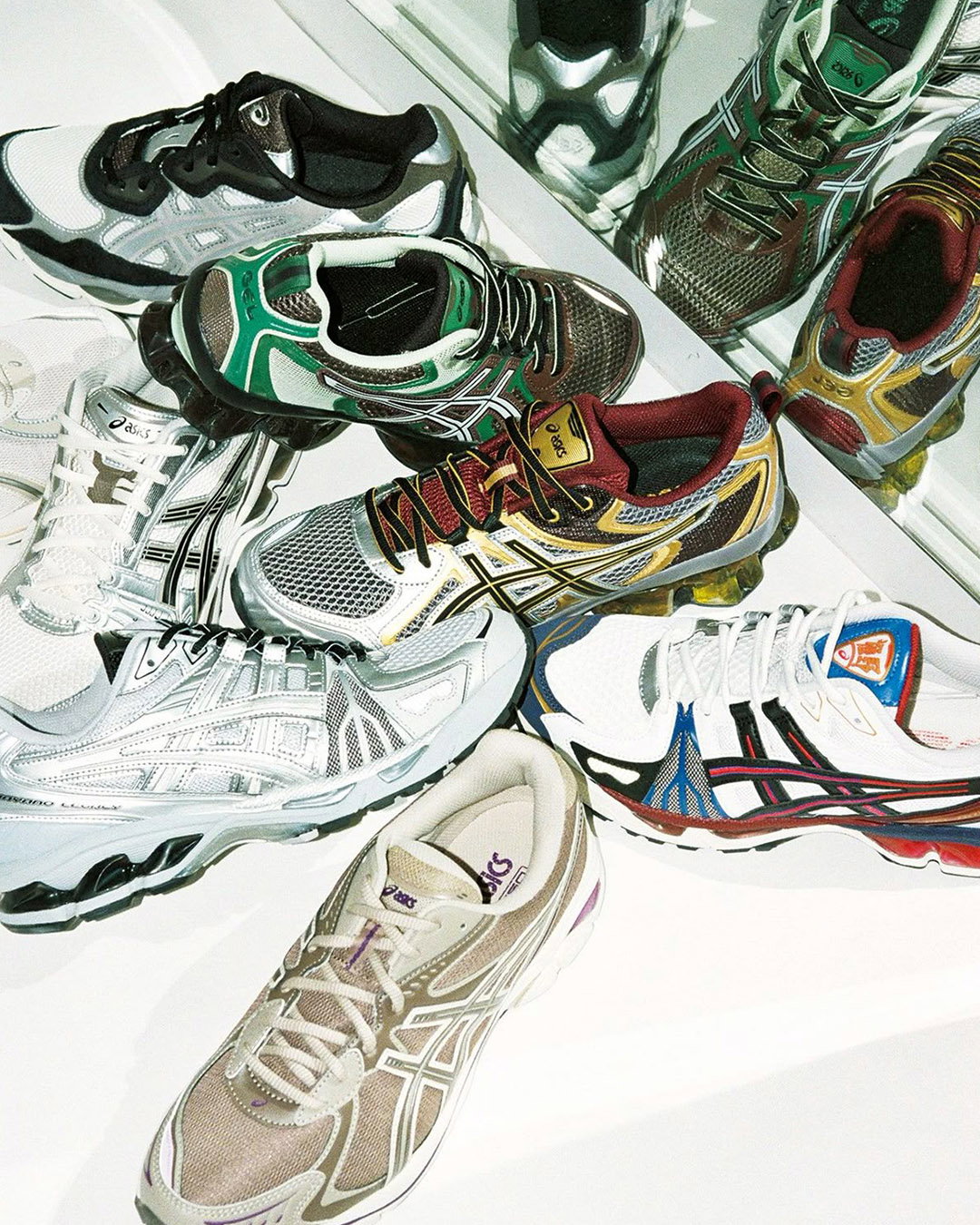 Assortment of colourful ASICS running trainers in various styles and colours arranged on a mirrored surface
