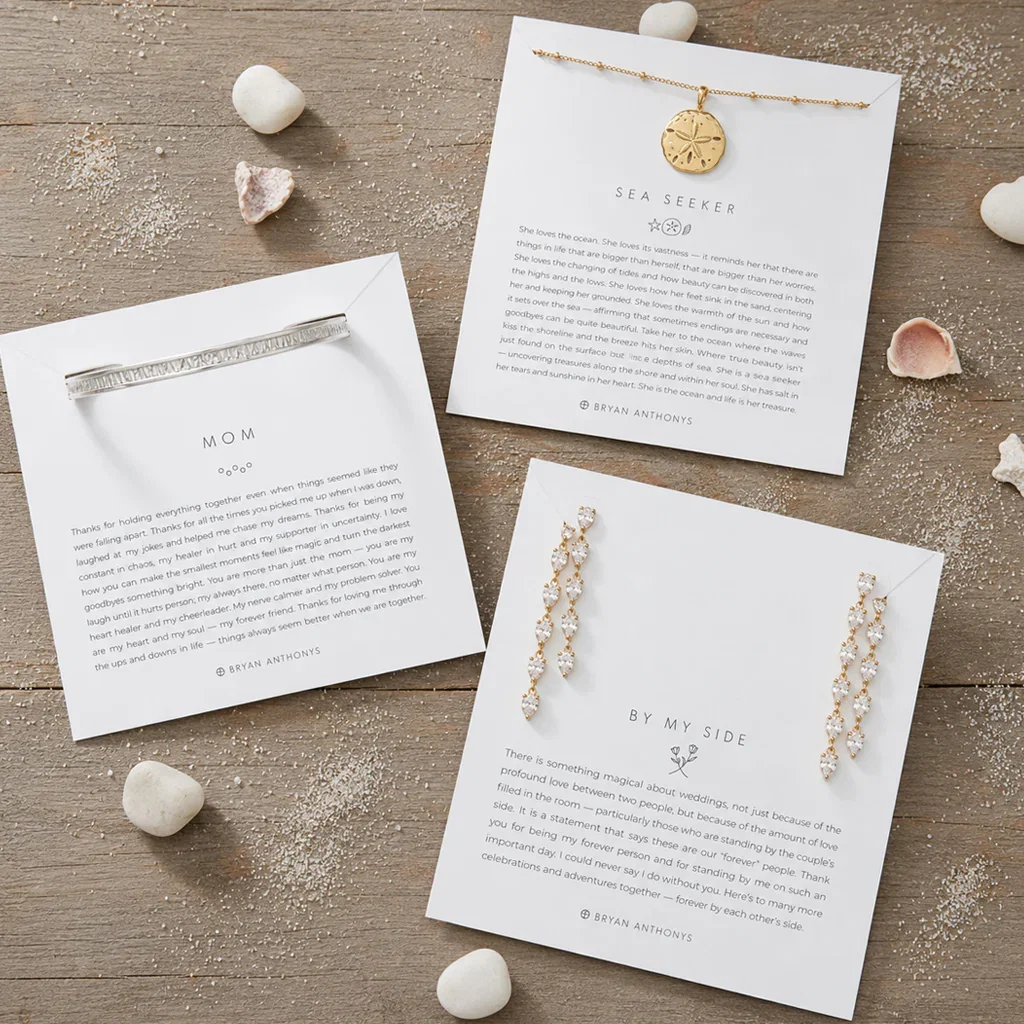 Flat lay of Bryan Anthonys jewelry cards featuring sea-themed pendants and earrings with heartfelt messages on wooden surface.