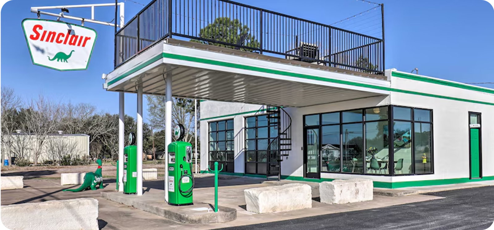 Converted gas station with vintage Sinclair pumps, rooftop deck, and a glass-front design.