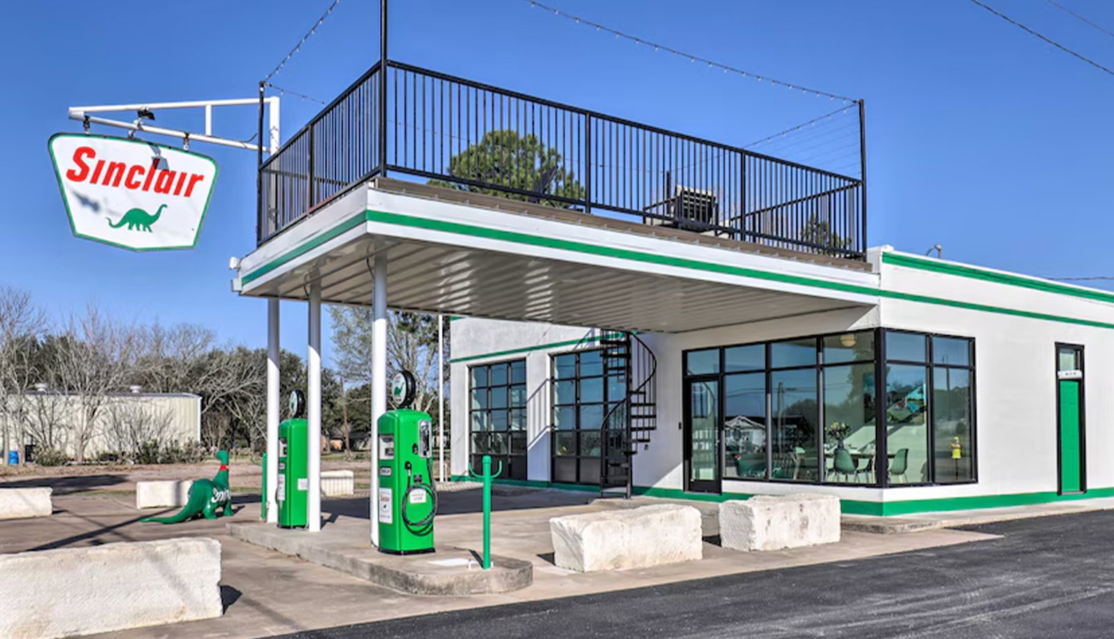 Converted gas station with vintage Sinclair pumps, rooftop deck, and a glass-front design.