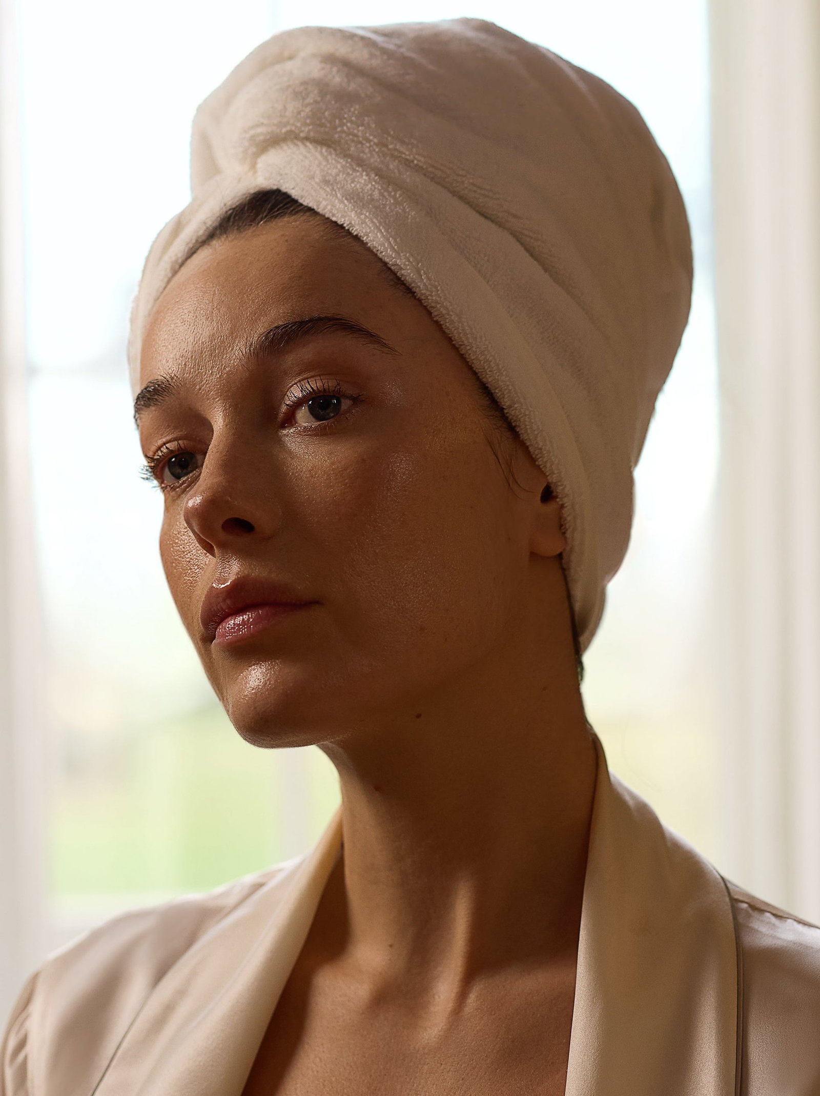 Image of model with hair wrapped in towel with glowing skin after using pro cleanser.