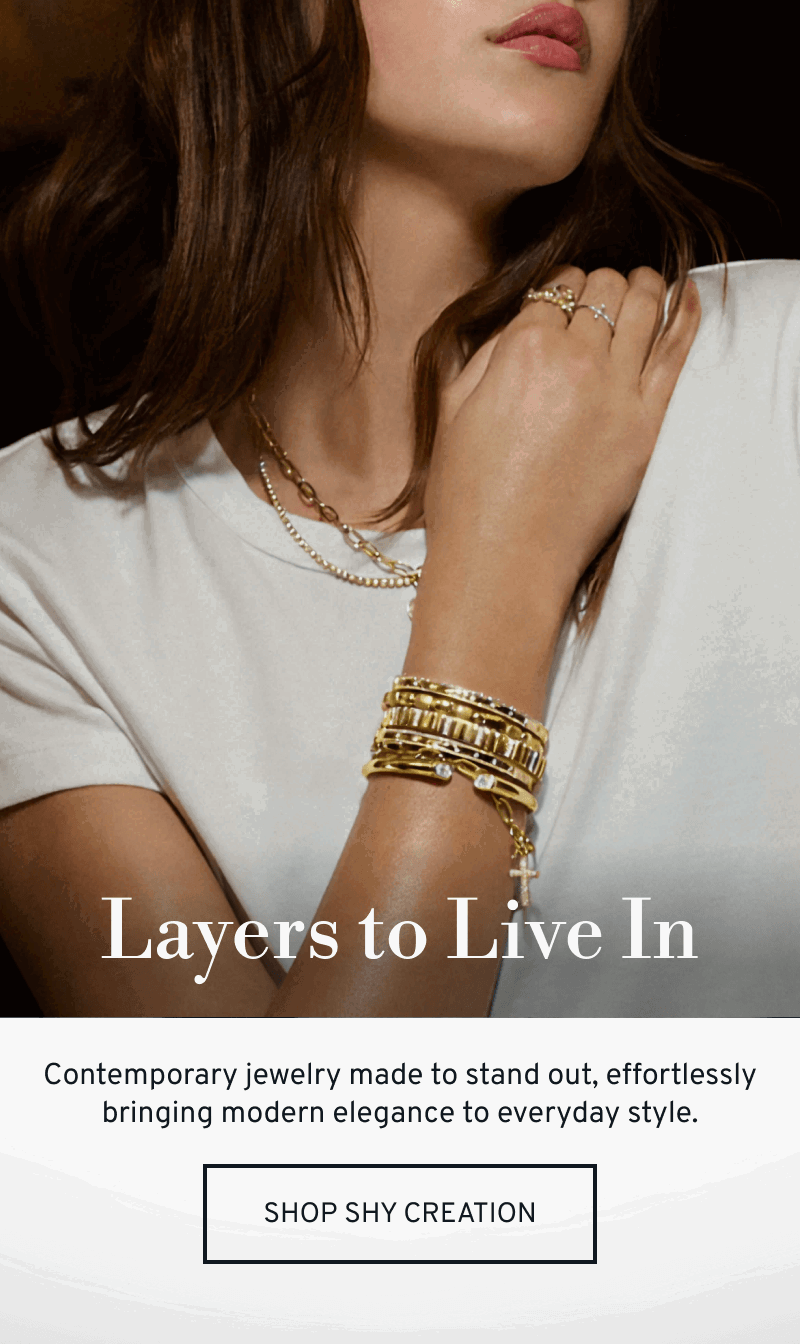 Model wearing layered Shy Creation gold bracelets, necklaces, and rings. Layers to live in. Click to Shop Shy Creation
