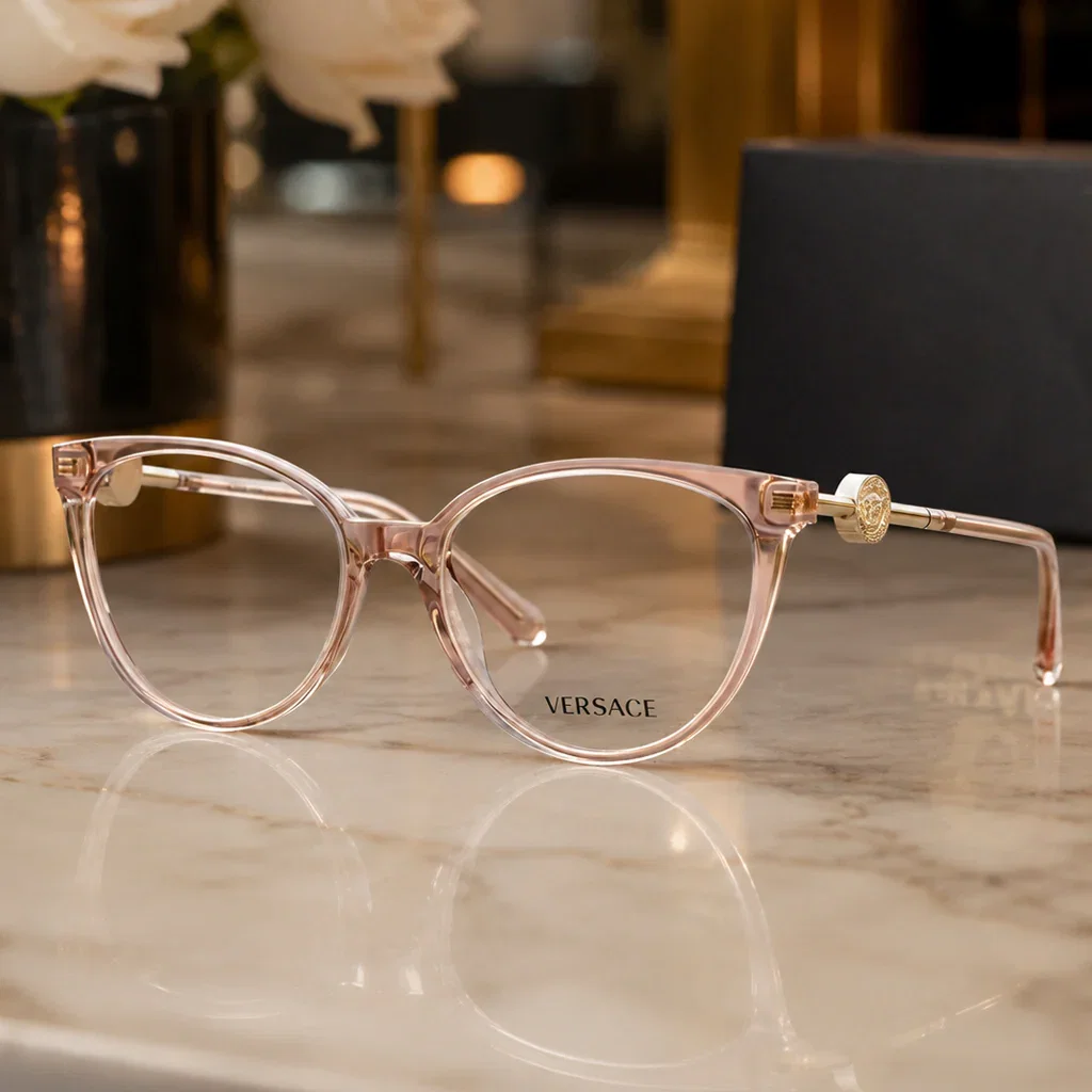 Versace eyeglass frames in clear rose gold on marble surface with luxury retail backdrop