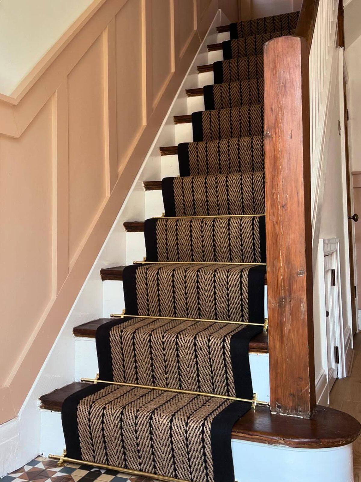 Peach-panelled walls with a patterned runner and geometric tiled floor at the entrance.
