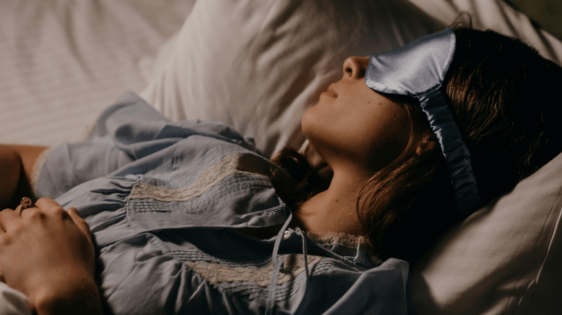 Image of woman wearing eye mask in bed
