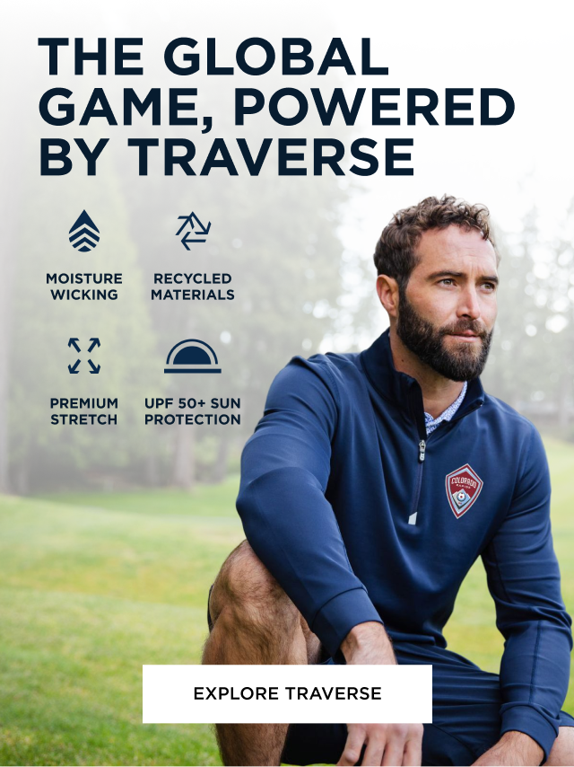 Man crouching down in wilderness wearing a quarter zip blue Traverse pullover | Explore Traverse
