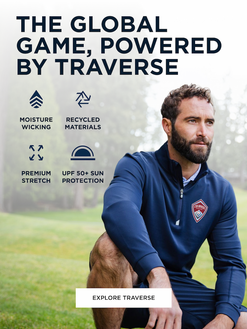Man crouching down in wilderness wearing a quarter zip blue Traverse pullover | Explore Traverse