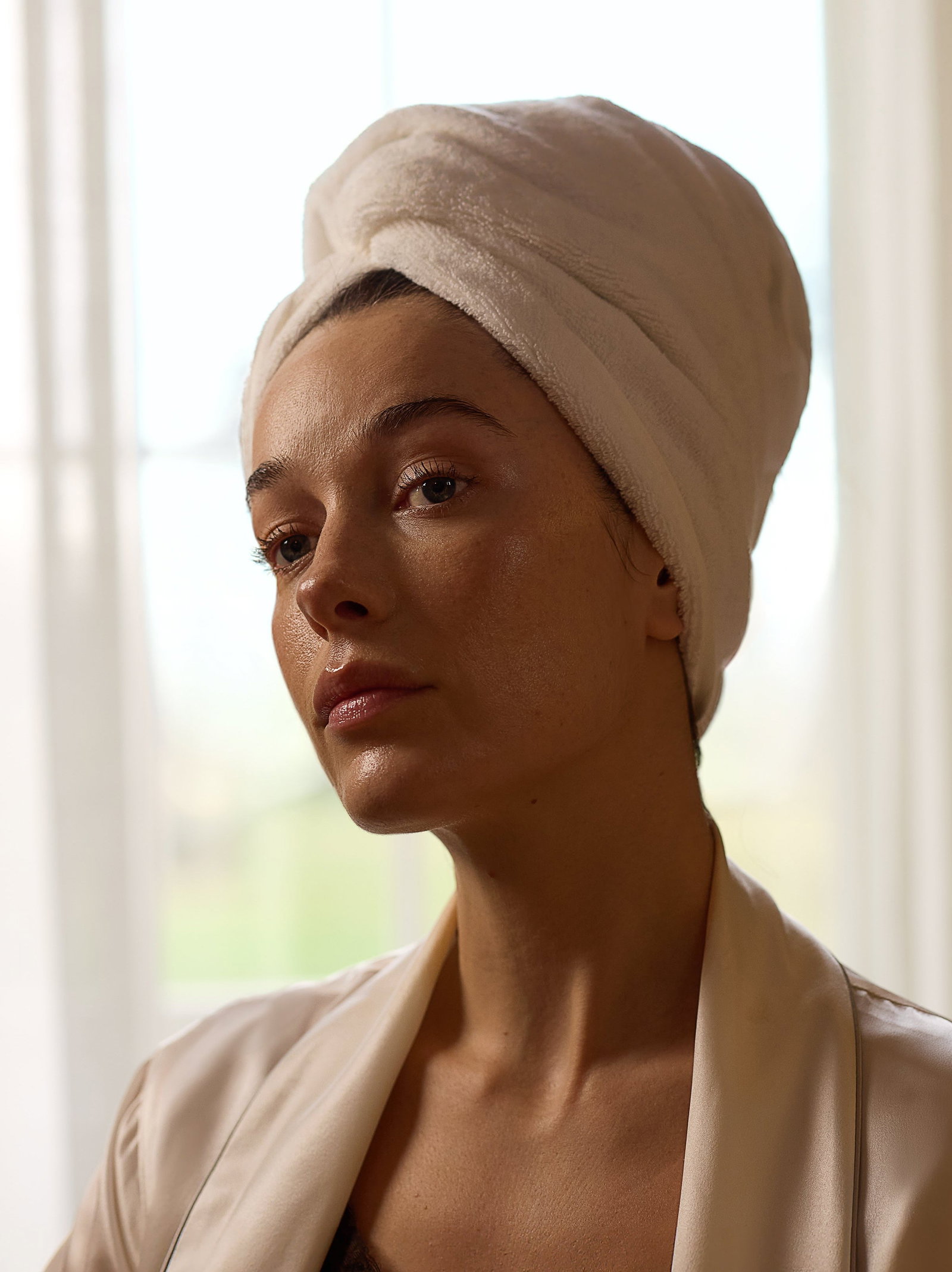 Image of model with hair wrapped in towel with glowing skin after using pro cleanser.